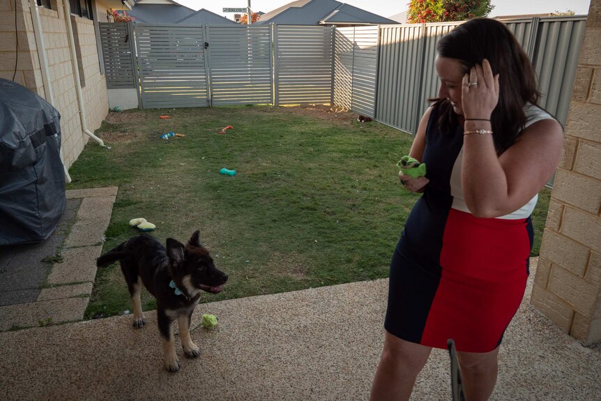Woman (Natasha Turfrey) in backyard with dog and dog toys scattered in background.