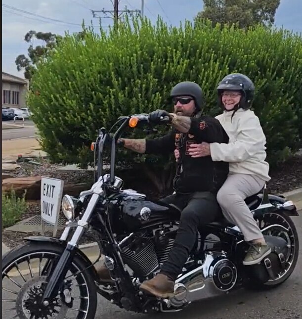 An elderly lady as a pillion passenger on a motorbike.