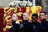 Four pallbearers carry the Queen's coffin draped with the Royal Standard of Scotland. 