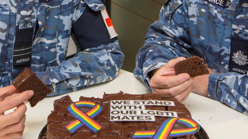 A closeup of a cake with a rainbow ribbon on it and writing saying we stand with our LGBTI mates