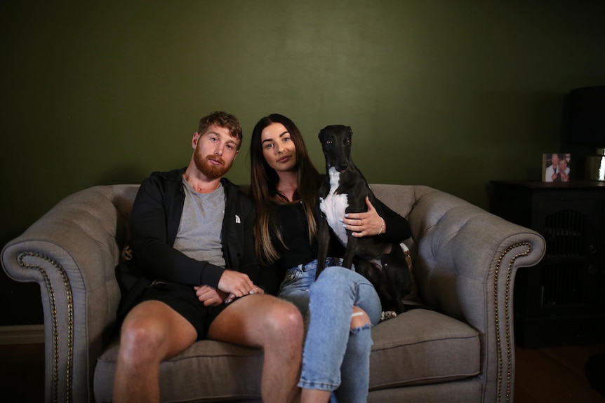 Danny and Jess sitting on the couch with their pet dog.