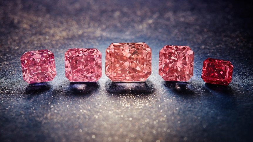 five sparkling pink diamonds on a table