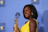 Viola Davis, dressed in yellow, holds her Golden Globe for Fences.