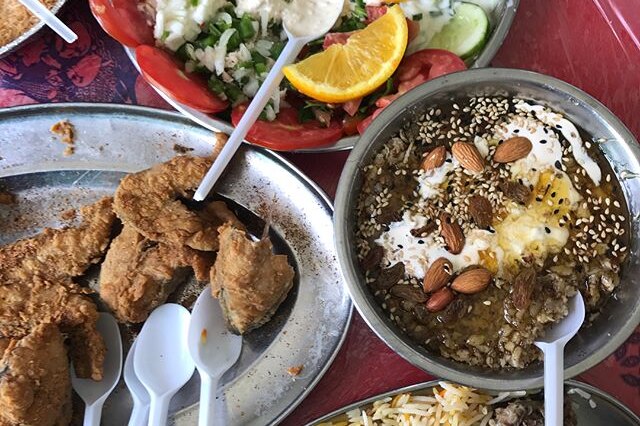 A feast of fried fish, steamed rise, salsa and a Yemeni sweet called fatteh drizzled with honey, nuts and cream.