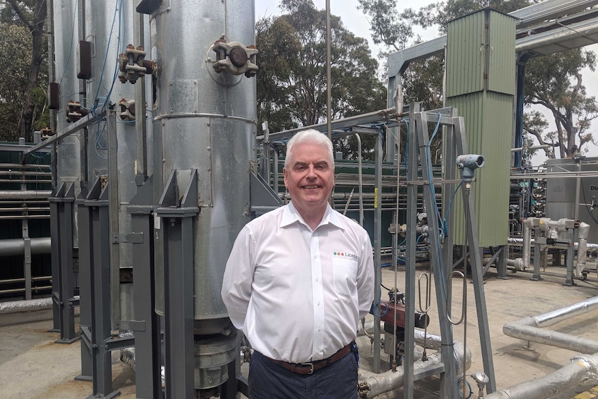Len Humphreys stands in front of metal pipes.
