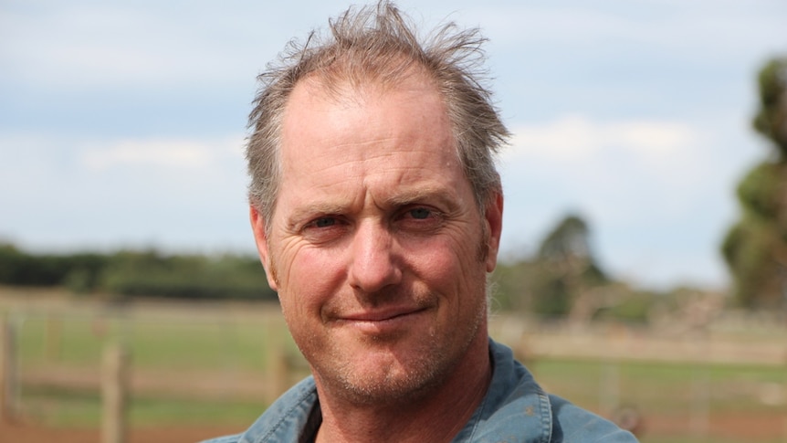 Dairy farmer Adam Jenkins leaning on a fence at his south-west Victorian property