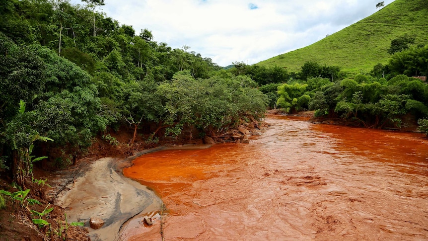 A river running with copper-coloured water from mine tailings in Brazil