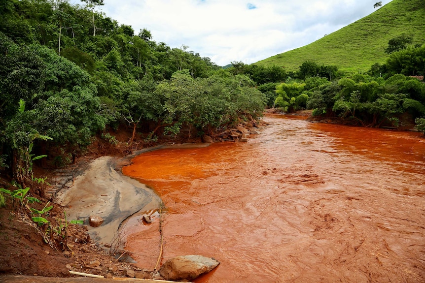 A river running with copper-coloured water from mine tailings in Brazil