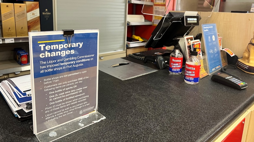 A sign on a bottle shop counter about alcohol restrictions