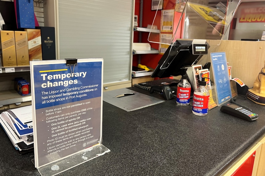 A sign on a bottle shop counter detailing alcohol restrictions.