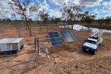 Dam in background with a small shed sitting next to solar panels and a ute in the foreground. 