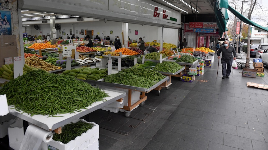 a man walking outside a fruit and vegetable shop