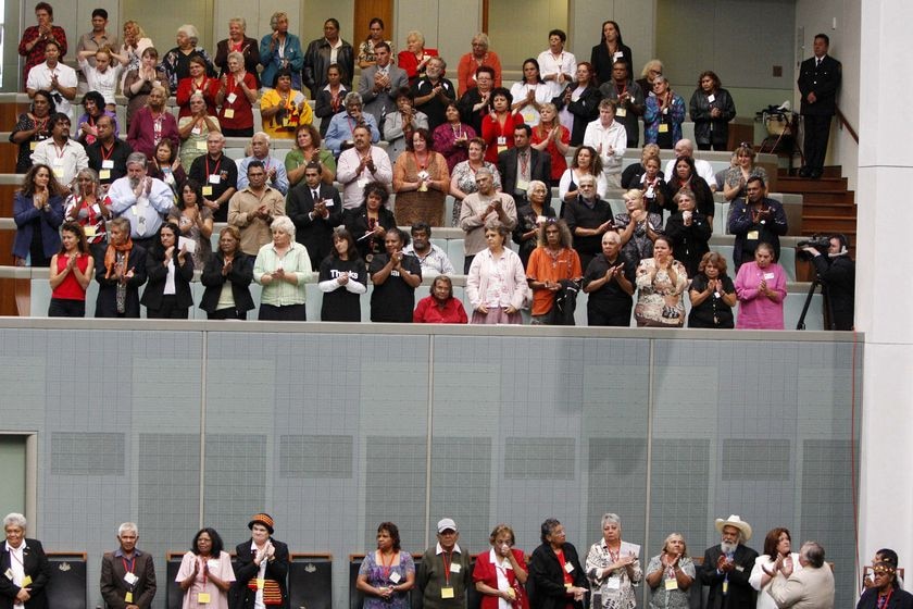 Indigenous community members stand and applaud