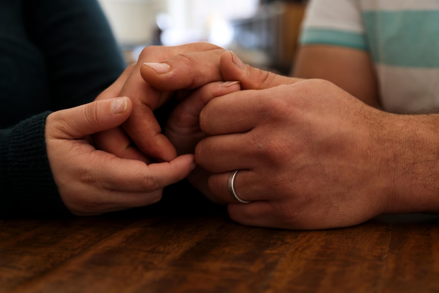A close-up photo of two pairs of hands touching each other.