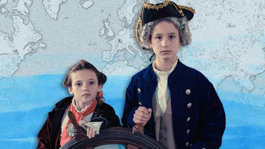 Two children role play Captain Cook and Joseph Banks in period costume holding on to an old ships steering wheel.