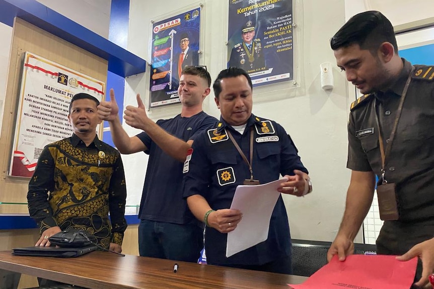 A man gives a thumbs up surrounded by police 