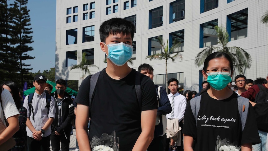 A group of Hong Kong protesters stand still, some hold flowers