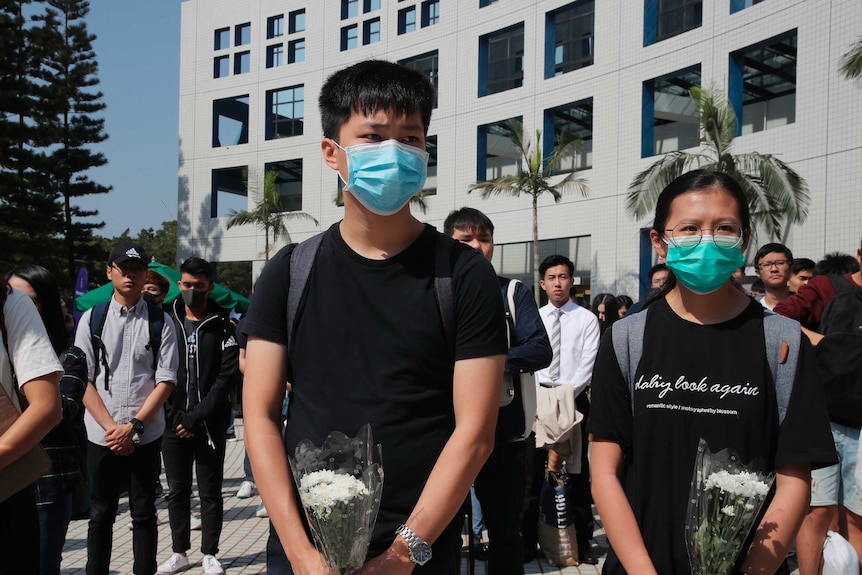 A group of Hong Kong protesters stand still, some hold flowers