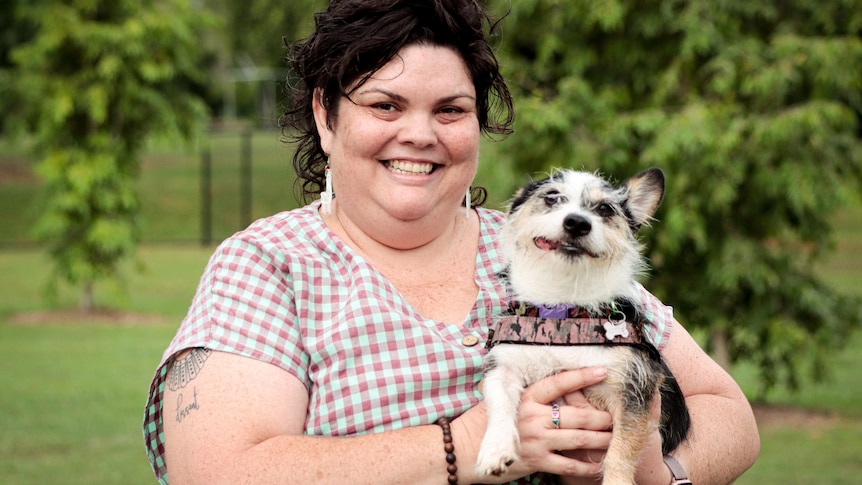 Portrait of a lady holding her dog in a park