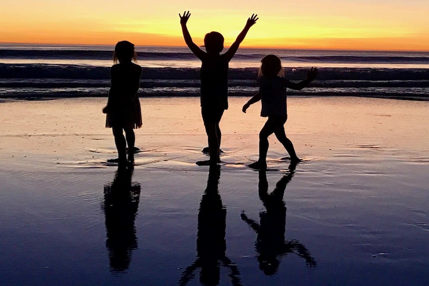 Children playing at sunset on the beach.