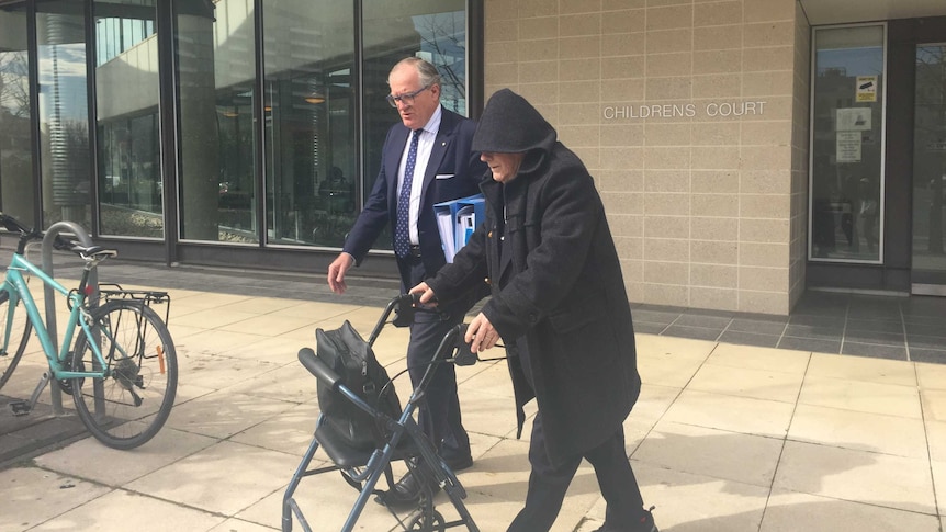 John chute (R) uses a walking frame outside the court building.