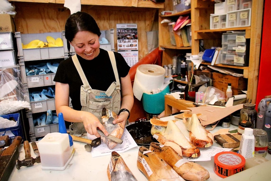 a woman at an arts station making wooden shoes