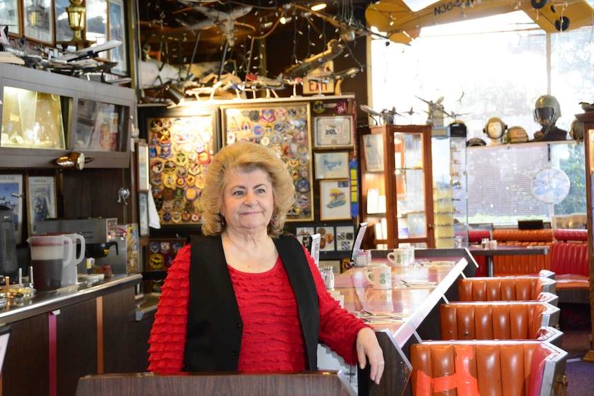 Lucia Roadenizer smiles as she stands in front of the front counter of her restaurant.