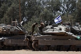 An image of two Israeli tanks with soldiers on top of them, on the right is an Israeli flag.