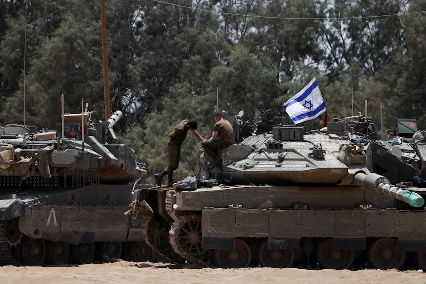 An image of two Israeli tanks with soldiers on top of them, on the right is an Israeli flag.