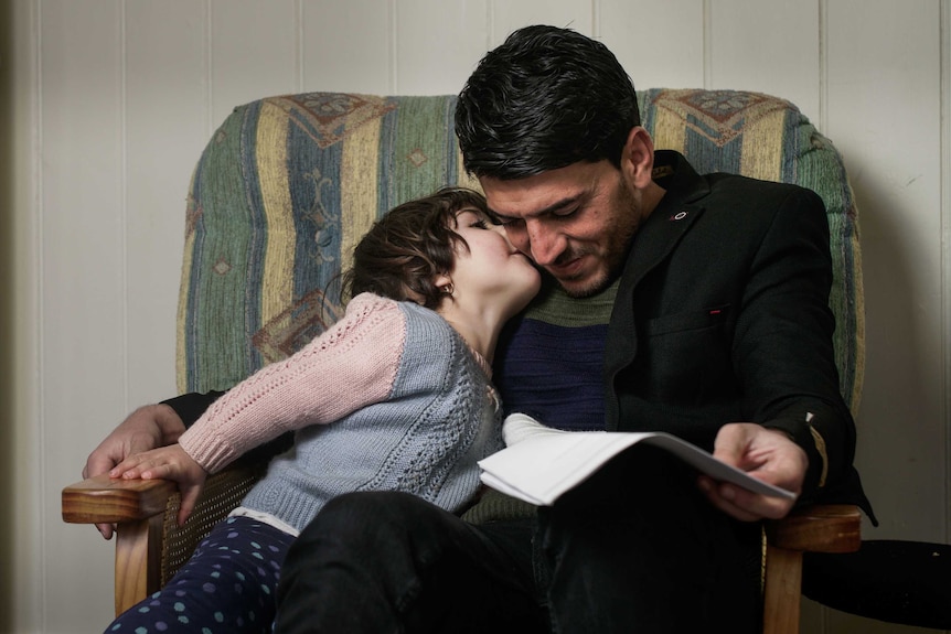 A man being kissed on the cheek by his 2-year-old daughter.