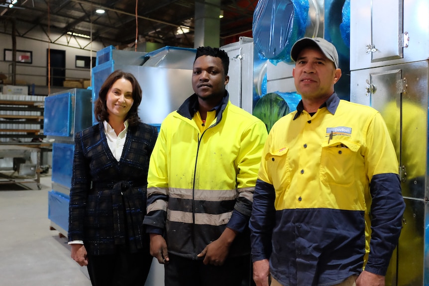 A lady stands with two men from culturally diverse backgrounds 