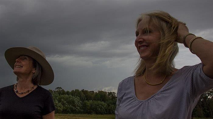 Black skies roll in overhead as farmers Suzanne Davis and Cathy Schuller look on near Bathurst