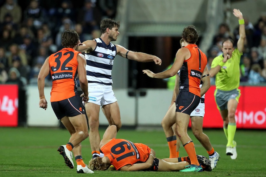 Nick Haynes from GWS lies on the ground after being knocked downby Tom Hawkins of Geelong (second left) during a marking contest