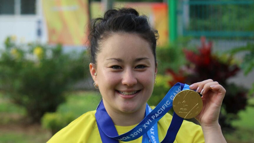 Erika Yamasaki wears her three gold medals at the Pacific Games.