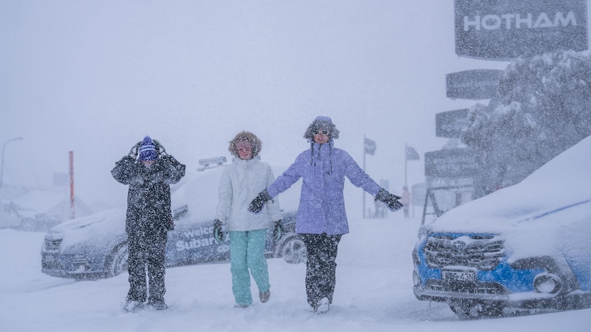 Three people stand in blizzard at Mount Hotham.