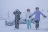 Three people stand in blizzard at Mount Hotham.