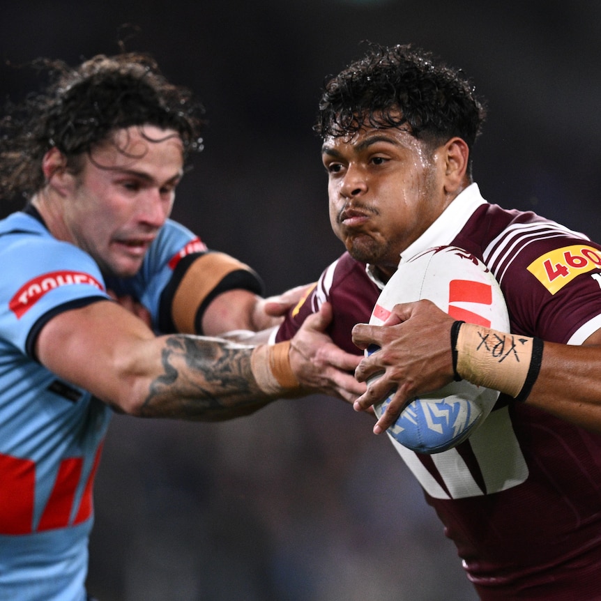 Selwyn Cobbo of the Maroons fends off Nicho Hynes of the Blues during State of Origin