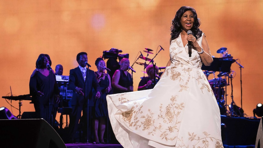 Singer Aretha Franklin sings in front of a band on stage