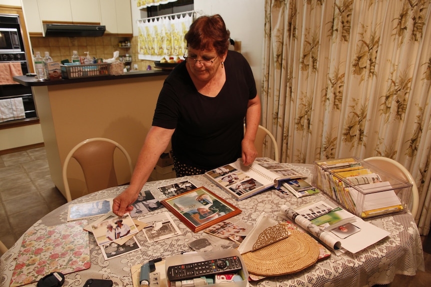 A woman is standing and looking down at photos on a table.