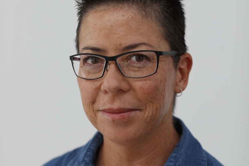 A woman with short dark hair and a blue shirt looking at the camera.