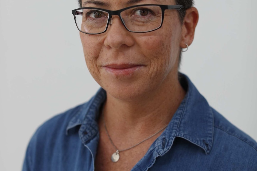 A woman with short dark hair and a blue shirt looking at the camera.