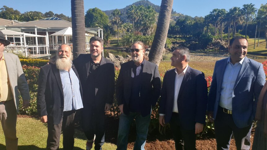 Russell Crowe stands with a group of men