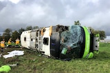 A bus lays on it's side with the front window and side smashed in.