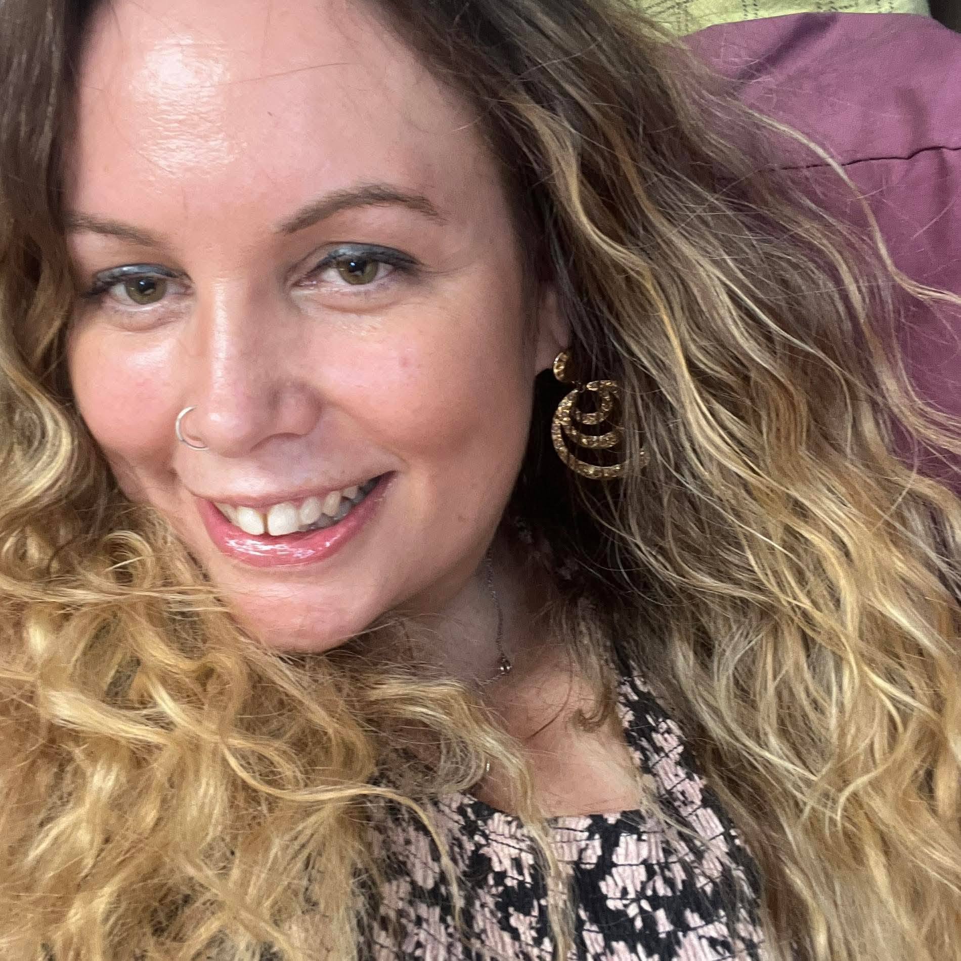 Closeup of a smiling woman with light brown /blonde hair looking at the camera.