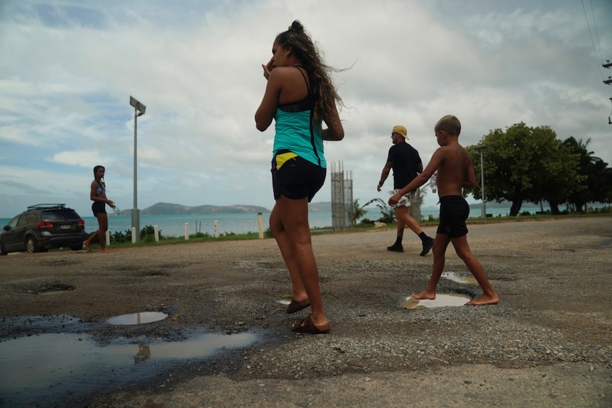 Children cross the road and walk towards the beach on Palm Island, North Queensland.