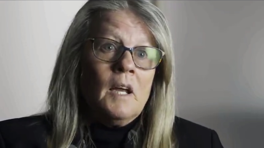 A screenshot of a video where Judy Mikovits is being interviewed. She is mid-sentence with a serious expression