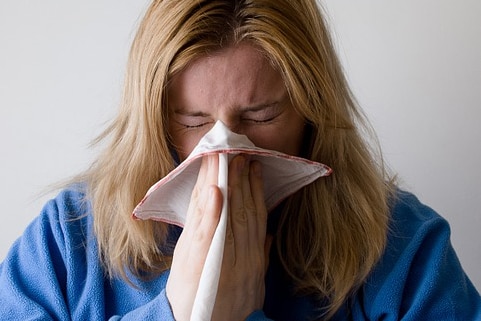 Woman sneezing into handkerchief.