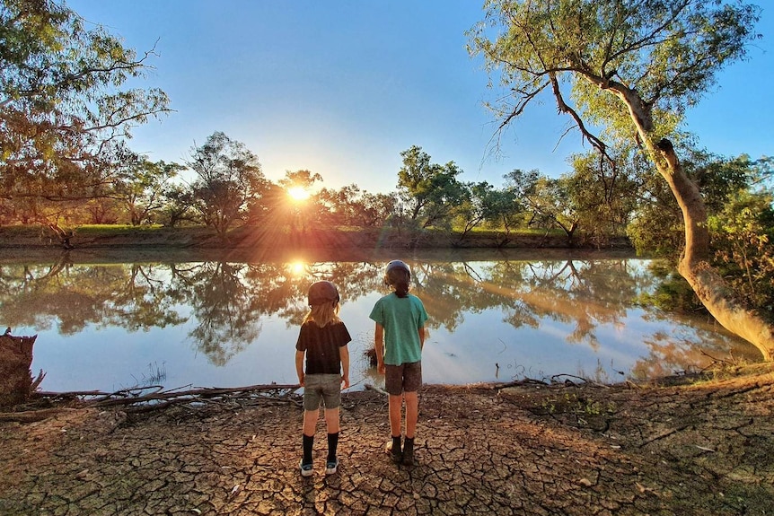 Two children watch a sunset by a dam near their temporary home at the Lass O'Gowrie homestead near Charleville.