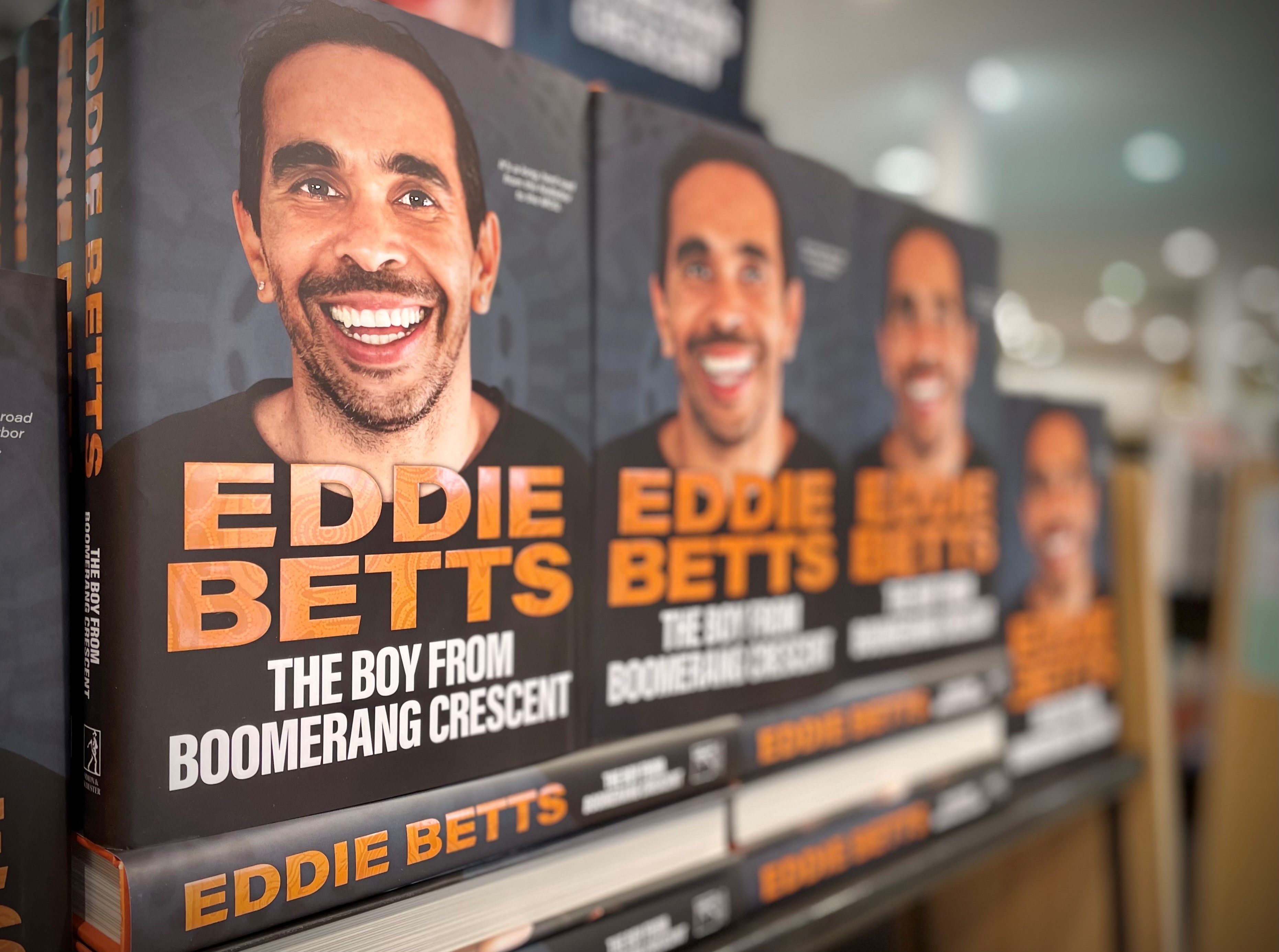 books of eddie betts on bookshelf, with his face on the front cover.