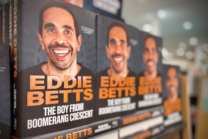 books of eddie betts on bookshelf, with his face on the front cover.
